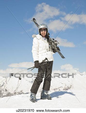 Stock Image - Woman with skis in mountain scene. Fotosearch
