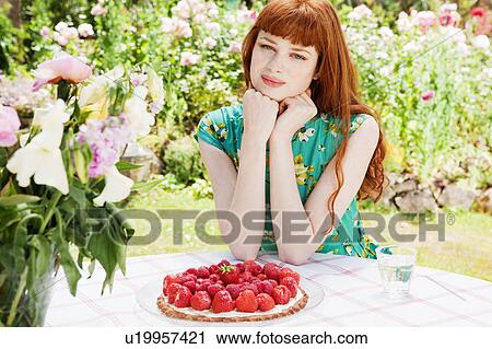 Stock Image - woman with strawberry tart in garden.. Fotosearch