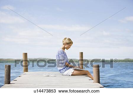 Woman working on her notebook lake-side View Large Photo Image Stock Image - Woman working on her notebook lake-side. Fotosearch