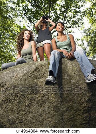 Women sitting on a rock in the woods View Large Photo Image Picture - Women sitting on a rock in the woods. Fotosearch