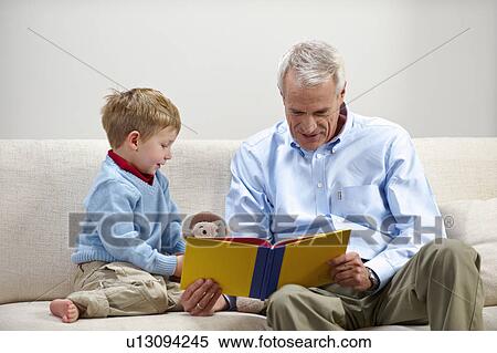 Stock Photography - Young boy and grandfather reading book. Fotosearch