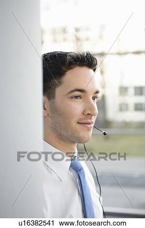 Stock Image - Young business man in office, headset. Fotosearch