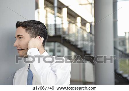 Stock Photo - Young business man in office, headset. Fotosearch