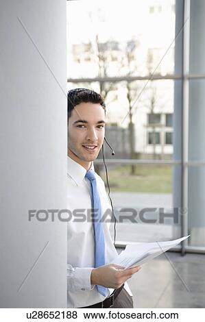 Stock Photo - Young business man in office, headset. Fotosearch