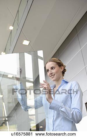 Stock Image - Young businesswoman writing on glass. Fotosearch