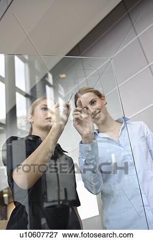 Stock Photo - Young businesswoman writing on glass. Fotosearch