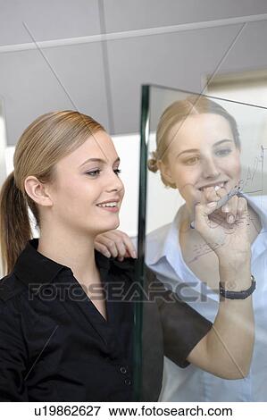 Stock Photo - Young businesswoman writing on glass. Fotosearch