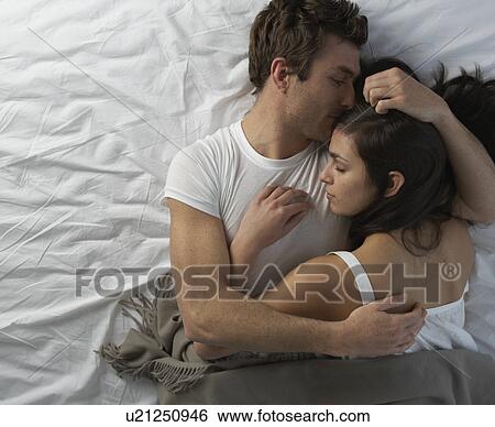 Stock Photograph - Young couple in bed embracing. Fotosearch