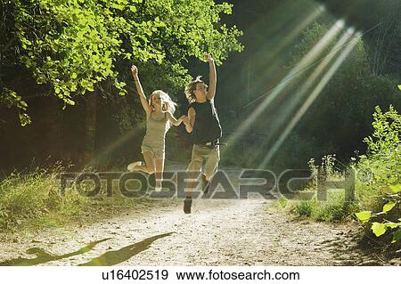Stock Photo - Young couple jumping in forest. Fotosearch