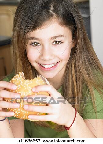 Stock Photo - Young girl eating a burger. Fotosearch