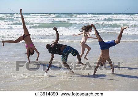 Stock Image - Young group frolicking on beach. Fotosearch
