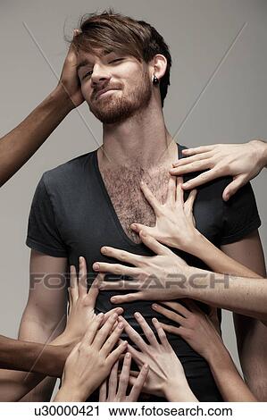 Stock Image - Young man being touched by hands. Fotosearch
