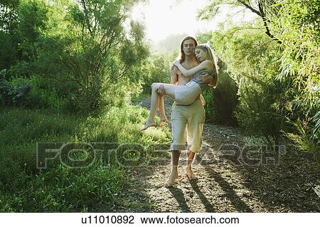 Stock Image - Young man carrying young woman. Fotosearch