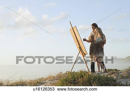Stock Image - Young man painting with young woman. Fotosearch