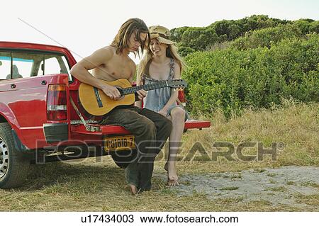 Young man playing guitar to young woman View Large Photo Image Stock Image - Young man playing guitar to young woman. Fotosearch