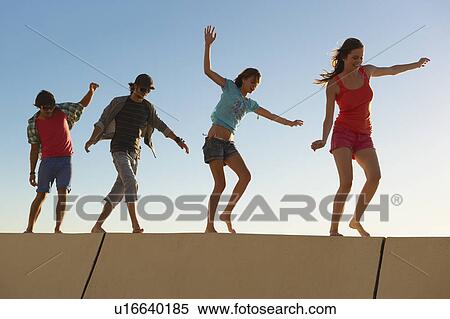 Stock Photography - Young people balancing on wall. Fotosearch
