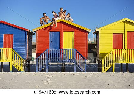 Young people sitting on top of beach hut View Large Photo Image Stock Photography - Young people sitting on top of beach hut. Fotosearch