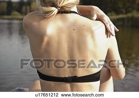 Stock Image - Young woman applying lotion to skin. Fotosearch