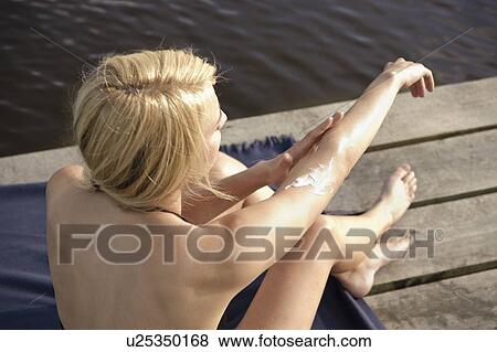 Stock Photo - Young woman applying lotion to skin. Fotosearch