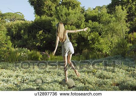 Young woman balancing on rock View Large Photo Image Stock Photograph - Young woman balancing on rock. Fotosearch
