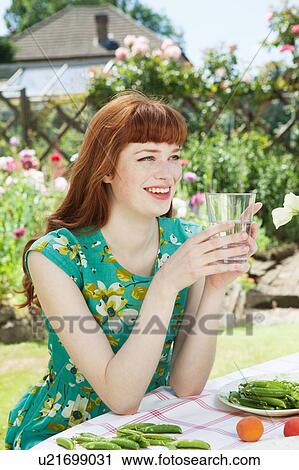 Stock Image - Young woman drinking water, smiling.. Fotosearch