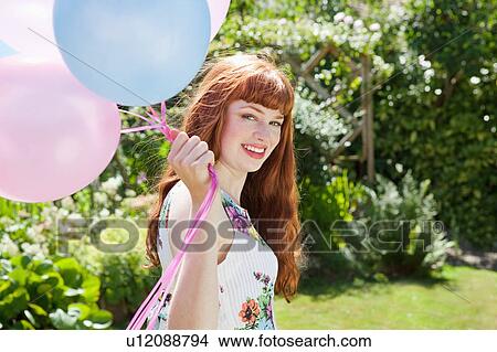 Picture - young woman holding balloons in garden.. Fotosearch