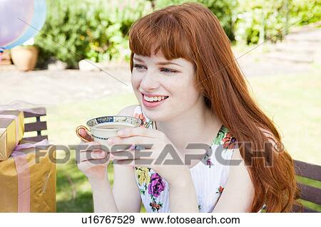Stock Photo - young woman holding tea cup, smiling.. Fotosearch