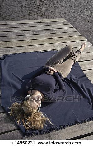 Young woman lies on blanket on jetty View Large Photo Image Stock Image - Young woman lies on blanket on jetty. Fotosearch