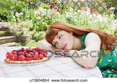 Picture - young woman looking at strawberry tart.. Fotosearch