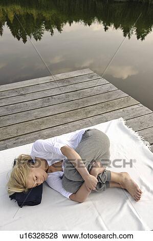 Young woman lying on blanket by lake View Large Photo Image Stock Photo - Young woman lying on blanket by lake. Fotosearch