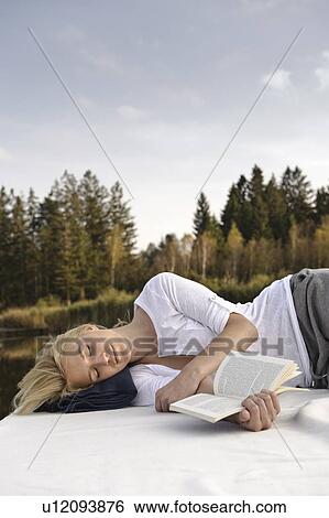 Young woman lying on blanket, reading View Large Photo Image Stock Photograph - Young woman lying on blanket, reading. Fotosearch