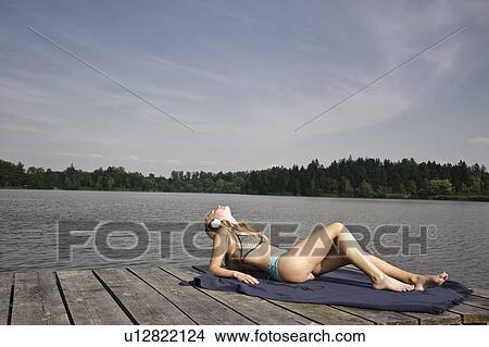 Picture - Young woman lying on blanket, relaxing. Fotosearch