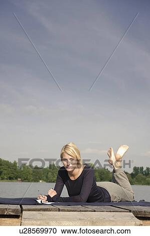 Young woman lying on blanket, writing View Large Photo Image Stock Image - Young woman lying on blanket, writing. Fotosearch