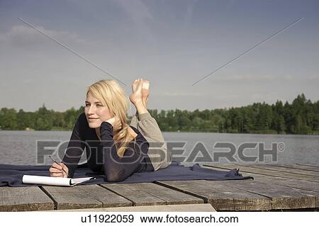 Young woman lying on blanket, writing View Large Photo Image Stock Photo - Young woman lying on blanket, writing. Fotosearch