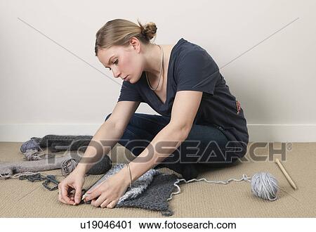 Stock Image - Young woman measuring knitting. Fotosearch