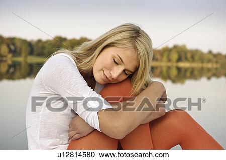 Young woman resting head on knee by lake View Large Photo Image Stock Image - Young woman resting head on knee by lake. Fotosearch