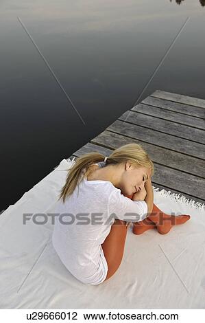 Young woman resting head on knee by lake View Large Photo Image Stock Image - Young woman resting head on knee by lake. Fotosearch