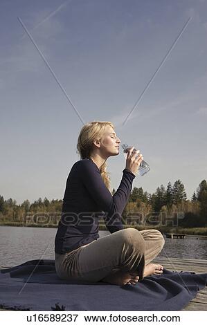 Young woman sitting on blanket, drinking View Large Photo Image Stock Photo - Young woman sitting on blanket, drinking. Fotosearch