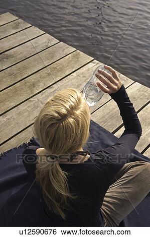 Young woman sitting on blanket, drinking View Large Photo Image Stock Photograph - Young woman sitting on blanket, drinking. Fotosearch