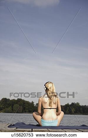 Stock Image - Young woman sitting on blanket. Fotosearch