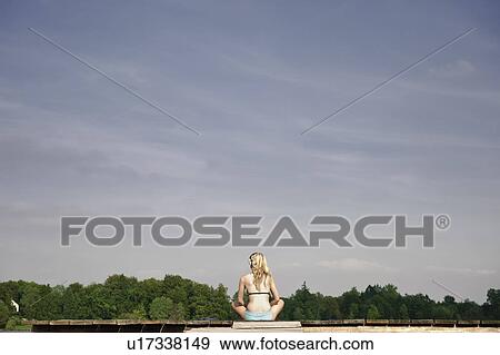 Stock Photo - Young woman sitting on blanket. Fotosearch