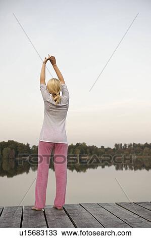 Young woman stretching by lake, yoga View Large Photo Image Stock Image - Young woman stretching by lake, yoga. Fotosearch