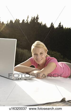 Stock Photo - Young woman using laptop, smiling. Fotosearch
