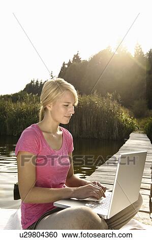 Stock Image - Young woman using laptop. Fotosearch