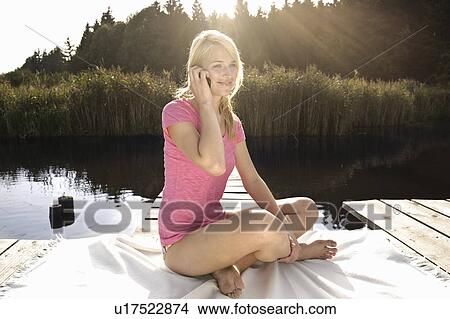 Young woman using mobile phone, smiling View Large Photo Image Picture - Young woman using mobile phone, smiling. Fotosearch