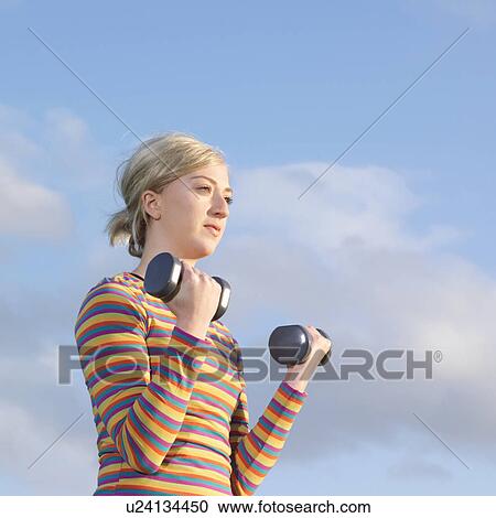 Stock Image - Young woman with dumbbells. Fotosearch