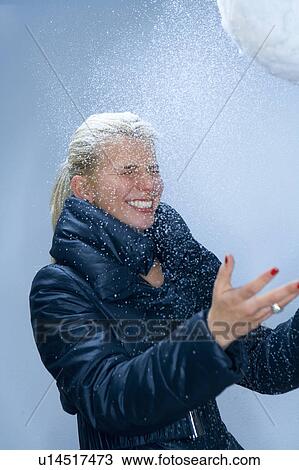 Stock Image - Young woman with snowball and snow. Fotosearch