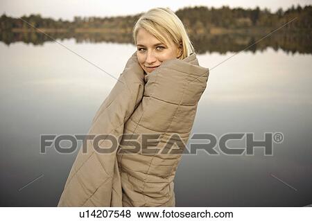 Stock Photo - Young woman wrapped in blanket, smiling. Fotosearch