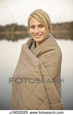 Stock Photo - Young woman wrapped in blanket, smiling. Fotosearch