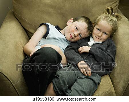 Stock Photograph - A brother and sister in an arm chair. Fotosearch